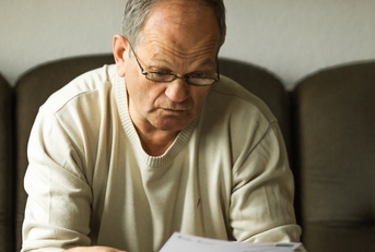 An old man looking at a bill