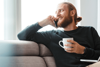 person relaxing on couch with phone and computer