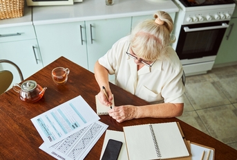 Older woman doing taxes on the kitchen table