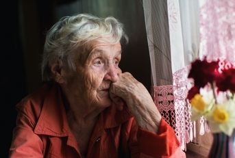 Sad elderly woman looking out window