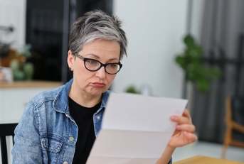 Confused Gen X retired woman reviewing a letter