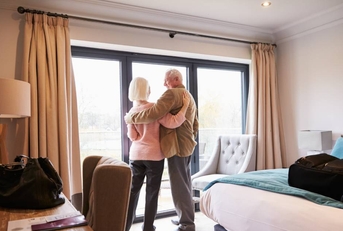 Senior Couple Arriving In Hotel Room On Vacation 