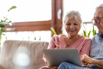 Smiling retired couple on the couch with laptop