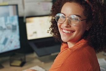 Woman wearing glasses smiling at the camera while working from home