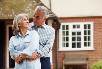 Retired couple hugging in front of the house