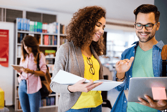 Two graduate students talking over laptop