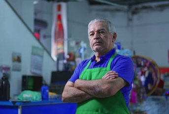 Older supermarket manager with crossed arms
