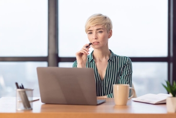 Business woman in her 40s with laptop, thinking