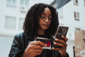 teenager with shopping bag on phone holding credit card