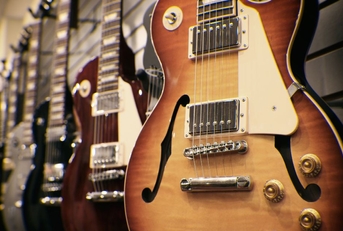 row of guitars on display for sale hanging in a music store