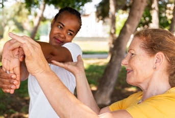 Older woman helping younger woman stretch