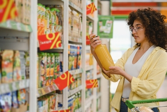 Woman grocery shopping holding orange juice checking the bottle