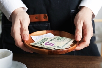 Server holding wood bowl with check and cash tips