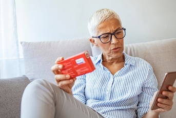 Senior woman looking at medication and phone suprised