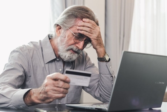 Stressed mature man holding credit card