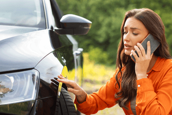Woman looking at damage from accident