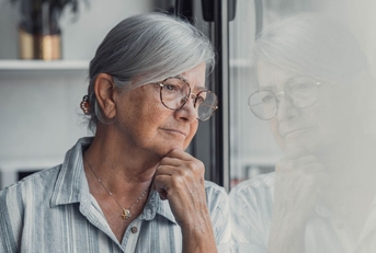 Concerned elderly woman looking out window