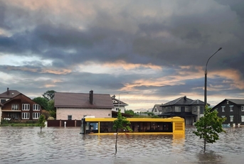 Flooded street with stranded bus and homes around
