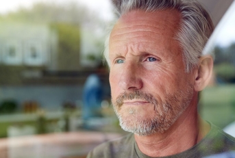 Pensive looking mature man looking out window