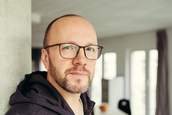 Bald man wearing glasses looking at camera