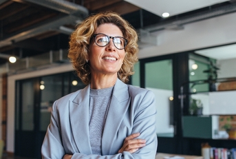 Woman in suit wearing glasses smiling at work