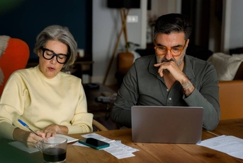 Mature couple managing finances and planning household budget at kitchen table