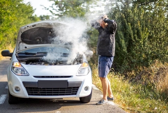 An anxious man near a broken car on the road