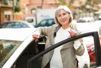 Mature woman standing besides white car