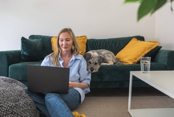 woman freelancer working on laptop with her dog at home