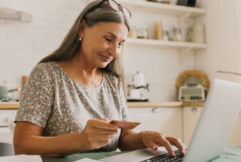 Happy senior woman making online payments of bill using laptop