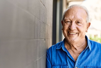 Smiling senior man leaning on concrete wall