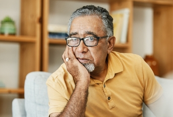 Older man looking worried resting his face on his hand