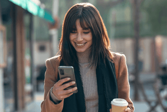 Woman looking at phone and holding coffee