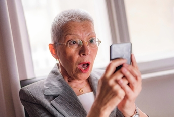 Older woman shocked looking at phone screen