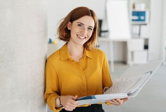 Young office worker in a yellow top holding a binder
