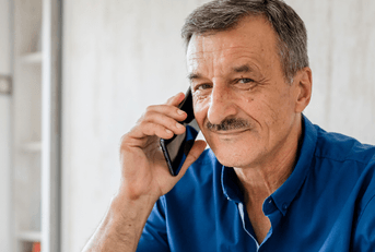 Man in his 60s on cell phone at home