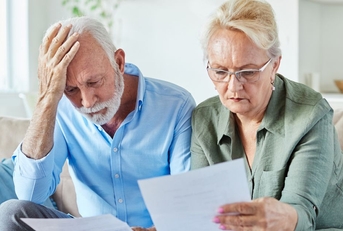 Worried senior couple looking at bills