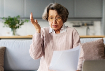 Senior woman surprised looking at paperwork