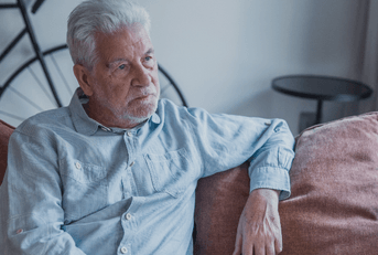 Older man sitting on couch looking distressed