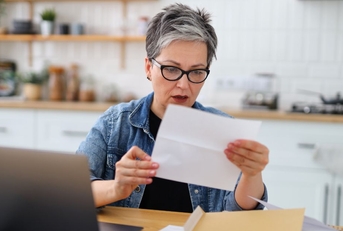 Shocked mature woman holding letter