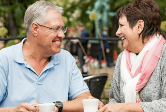 Couple in their 60s sitting outside having coffee