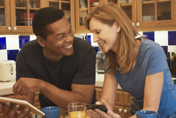 Couple in their 50s looking at tablet in kitchen