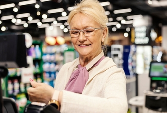 Senior paying at self-checkout of grocery store