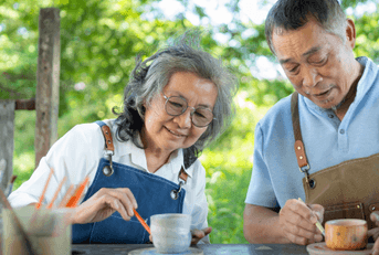 Senior couple doing pottery outside home