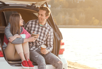Couple sitting in car on beach while traveling