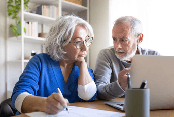 Boomer couple looking at emergency fund on laptop