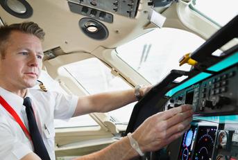 male pilot checking control panel in airplane cockpit