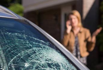 Woman Phoning For Help After Car Windshield Has Broken 