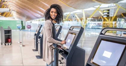 woman using check in machine at airport to avoid checked bag fees