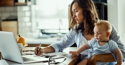 Working mother taking notes while calculating budget